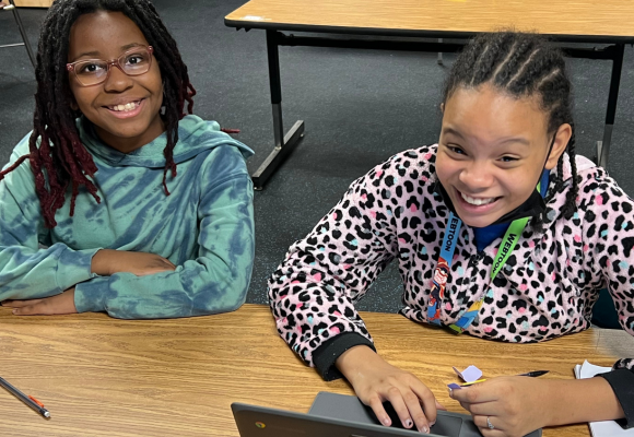 Two RPS middle schoolers smiling at their afterschool program while playing on the computer.