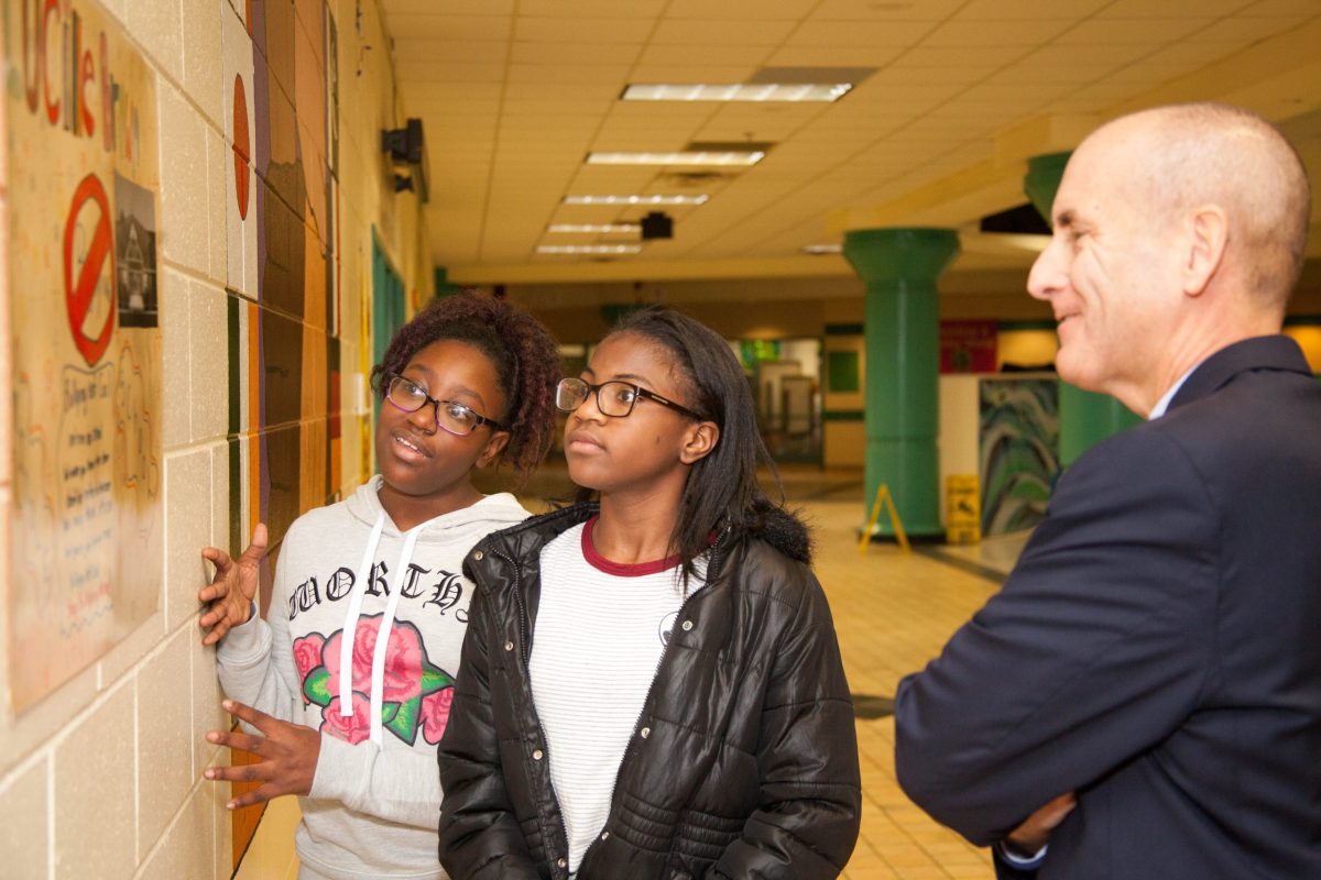 Former Board Chair, Steve Rogers, looking at art on the wall of a Richmond Public Middle School with two students in NextUp programs.